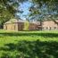 Exterior photo of Caryl Community Center showing the new pavilion and historic school sections. The exterior is brick and set back on a green lawn surrounded by trees.