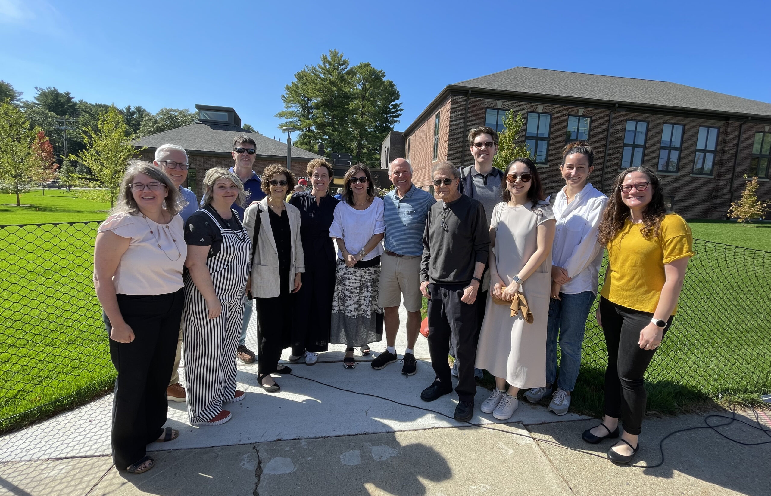 Group photo of the FM team with the building committee outside the entrance of the Caryl Community Center on a bright summer day.